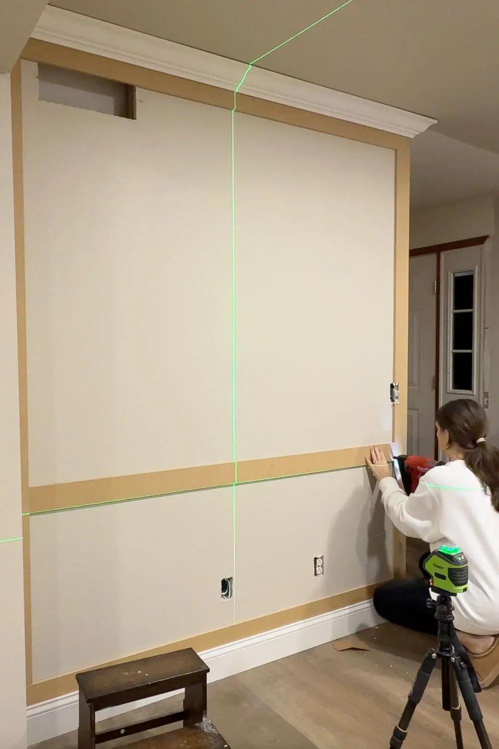 Installing the center chair rail panel picture frame wall trim using a green laser level for straight, even panel spacing.