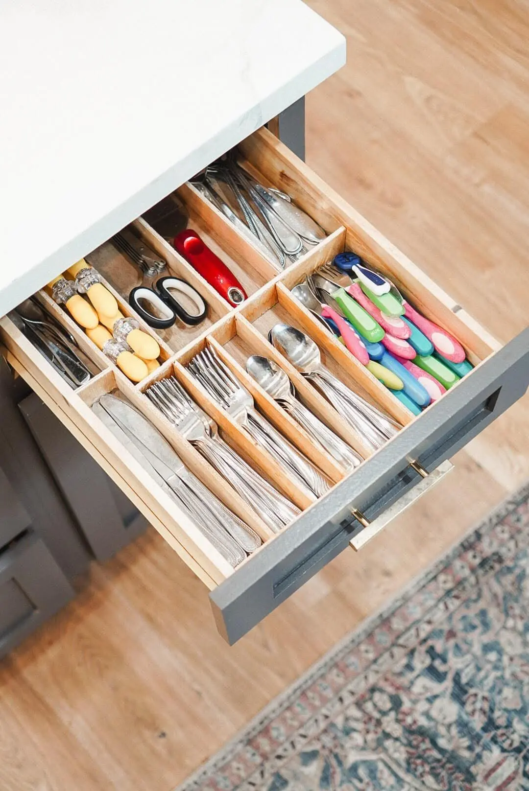 Custom DIY silverware drawer organizer with wood dividers, neatly sorting forks, spoons, knives, and kids utensils for better kitchen drawer organization.