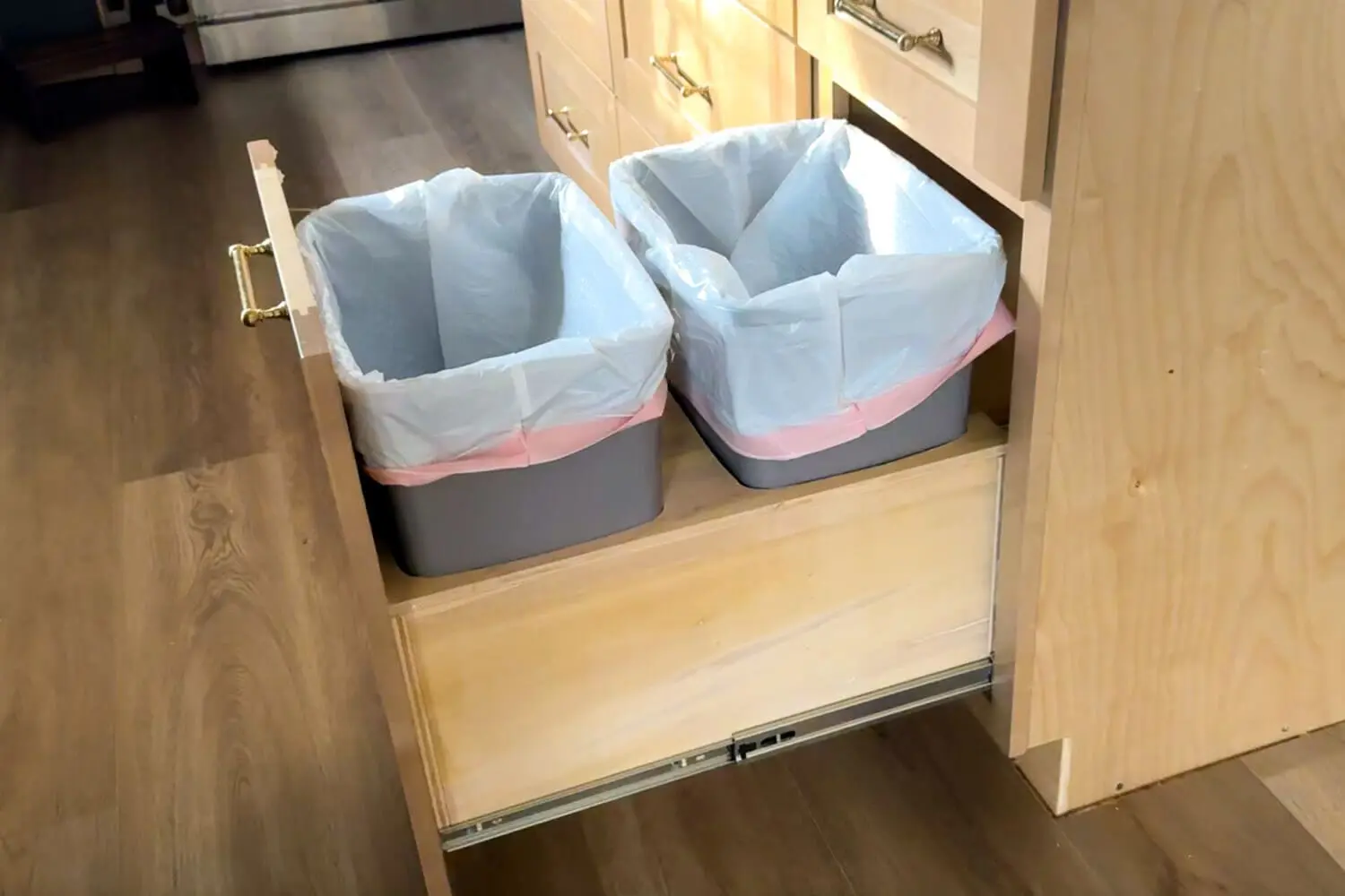 DIY double trash can pull-out cabinet with two bins on a sliding drawer, hiding garbage inside a base cabinet for cleaner, more functional space.