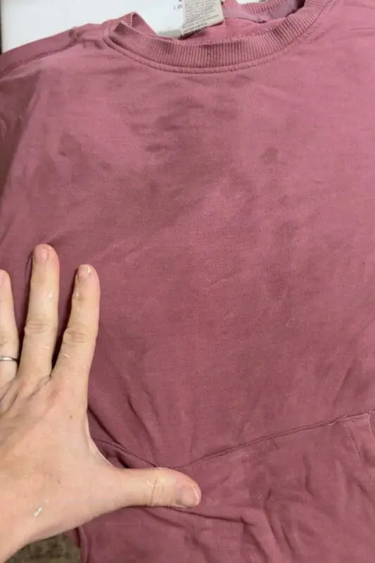 Kids sweatshirt laid flat showing dark, grimy areas and fabric buildup before a deep clean to remove stubborn odors.