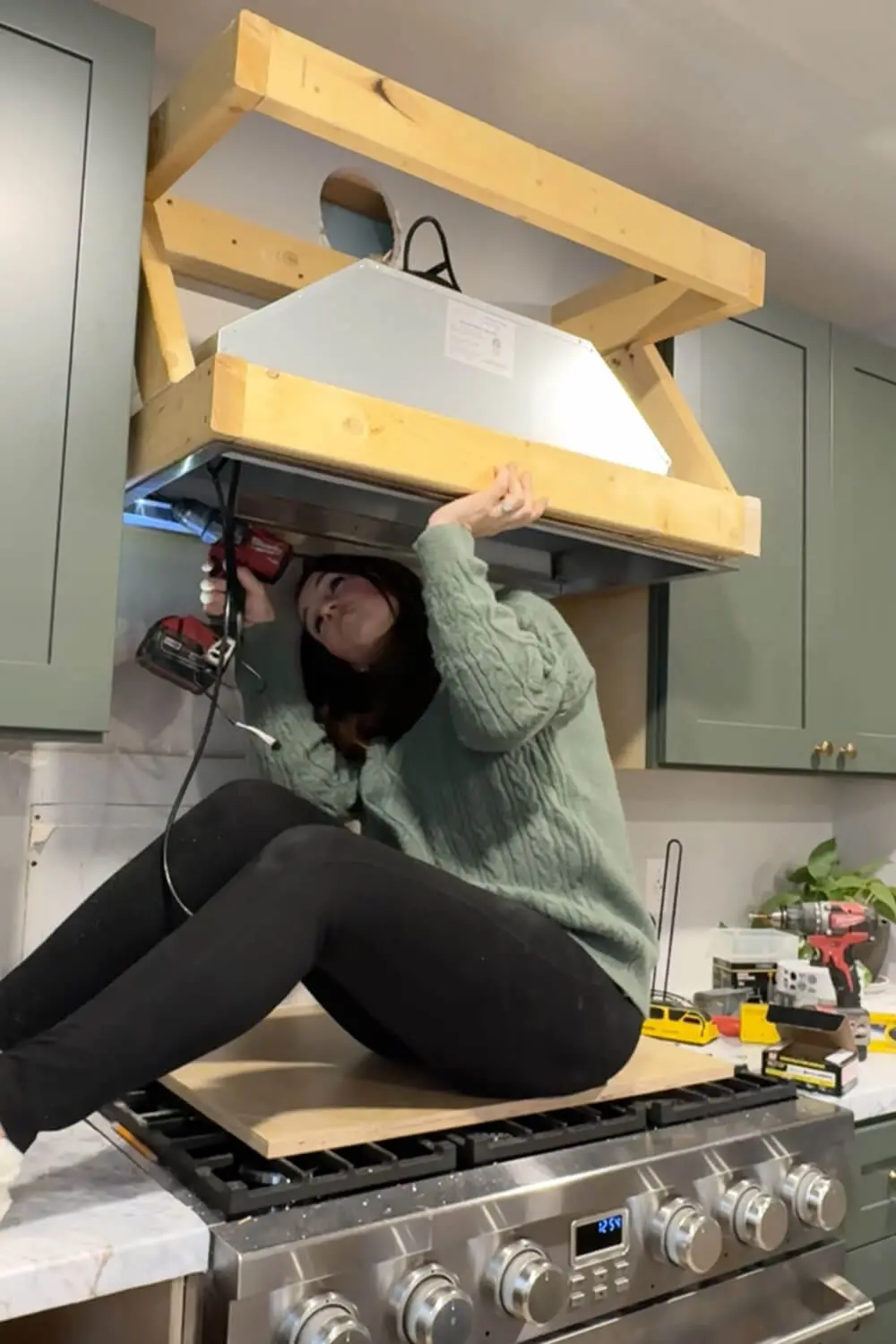 Installing the range hood insert into the bottom frame of a DIY range hood cover above the stove.