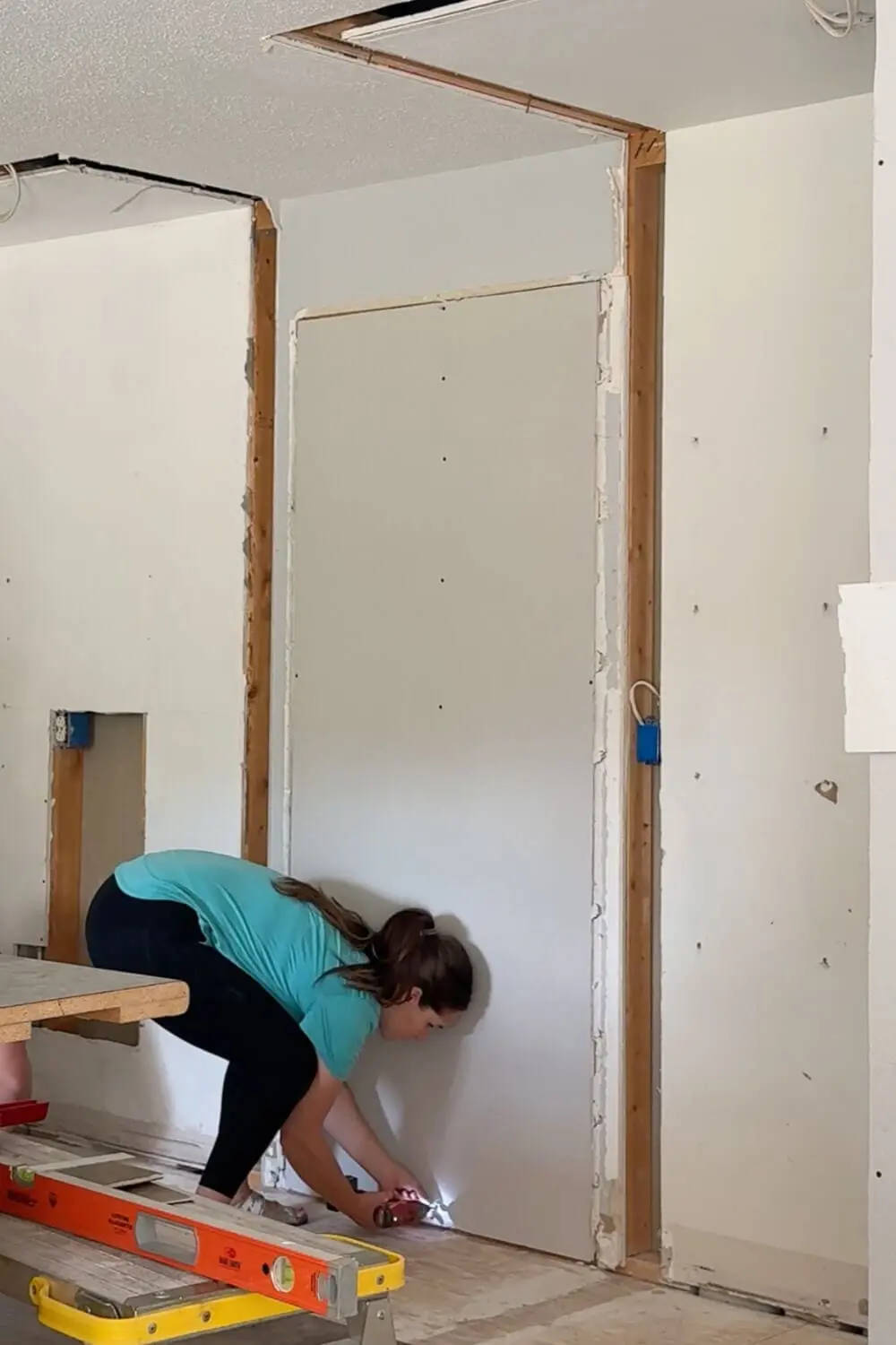 Attaching drywall to close off the kitchen doorway to the dining room so we can build a full wall of cabinets in its place.