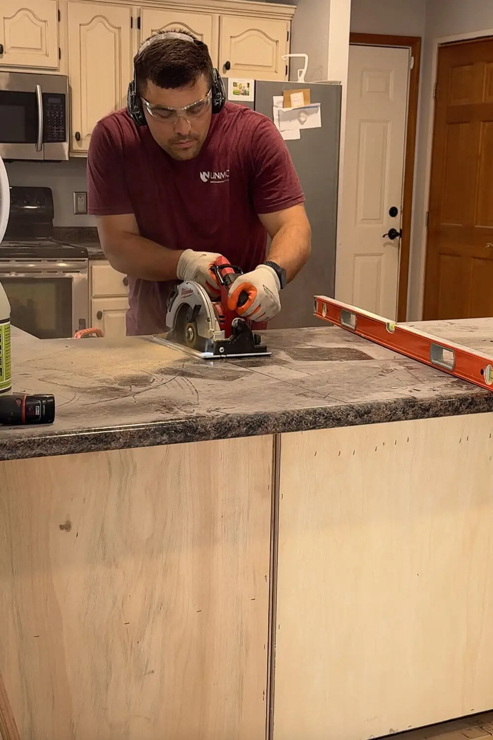 Wearing safety glasses and ear protection, we use a circular saw to cut through the old kitchen peninsula countertop during the demo before our kitchen renovation.