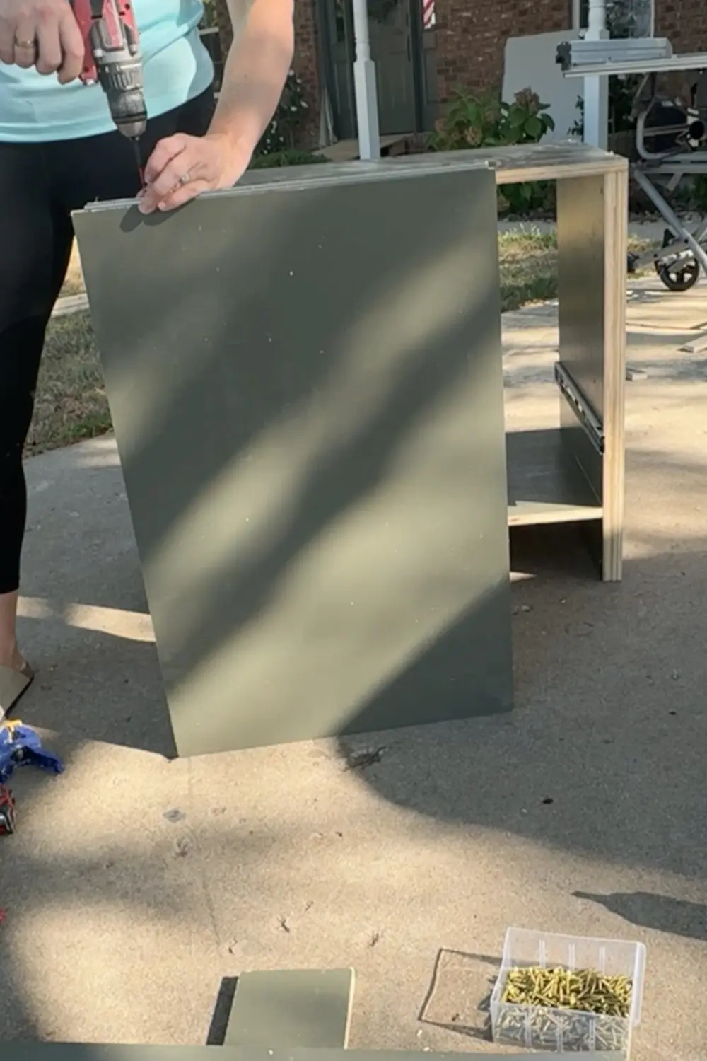 Attaching the second half of the drawer slide to a painted plywood shelf to create a pull-out shelf for the DIY built-in bookshelves.