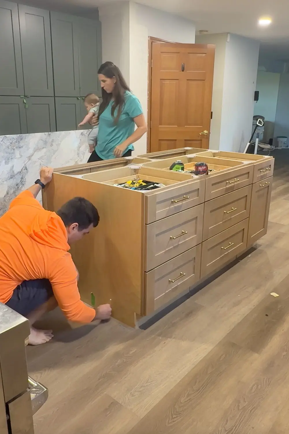 Tracing the outline of the DIY kitchen island cabinets on the finished floor to mark where to cut the flooring out so the island can be installed and secured to the subfloor.
