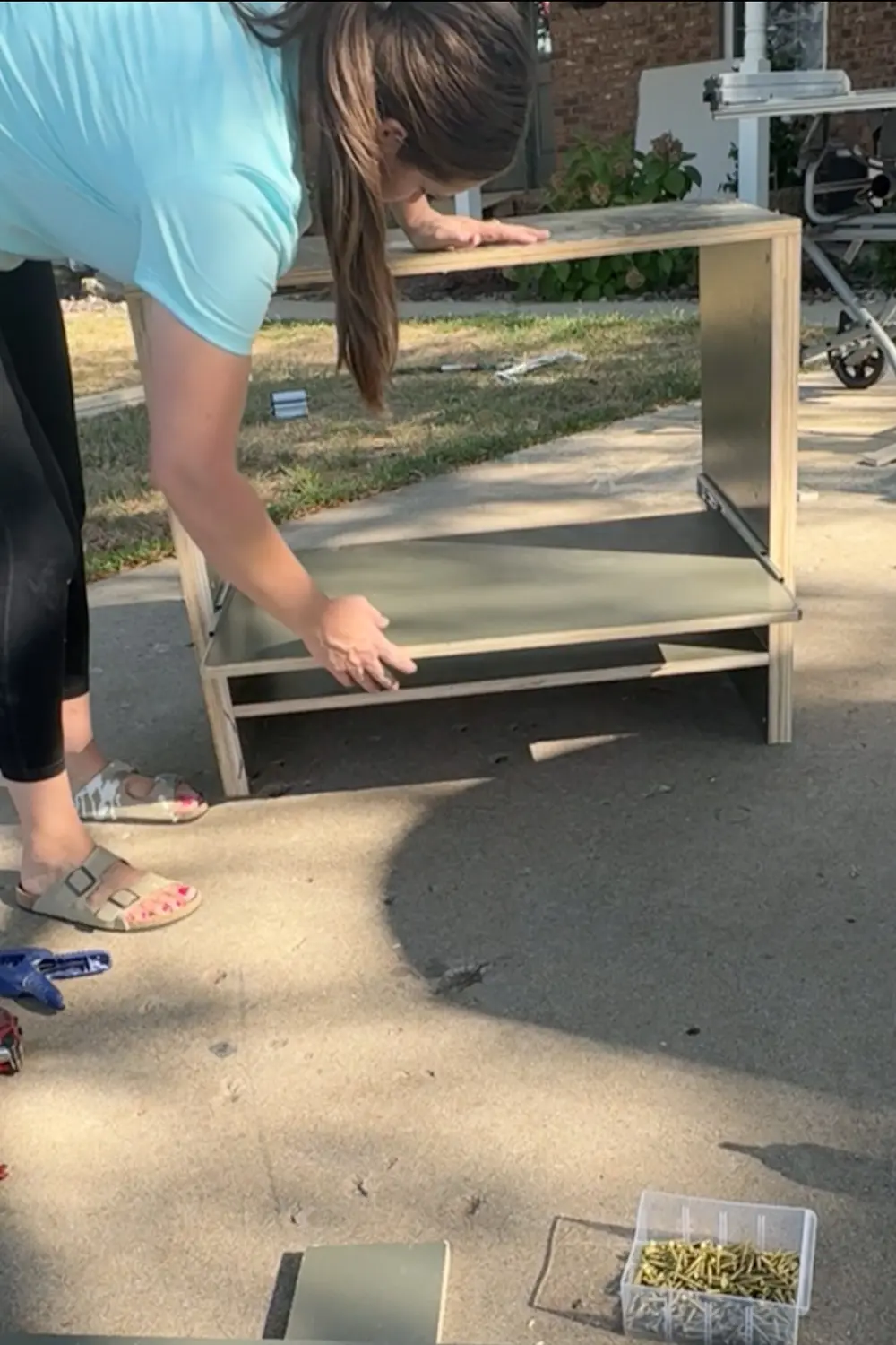Sliding the painted pull-out shelf into the cabinet base after installing the drawer slides for the DIY built-in bookshelves.