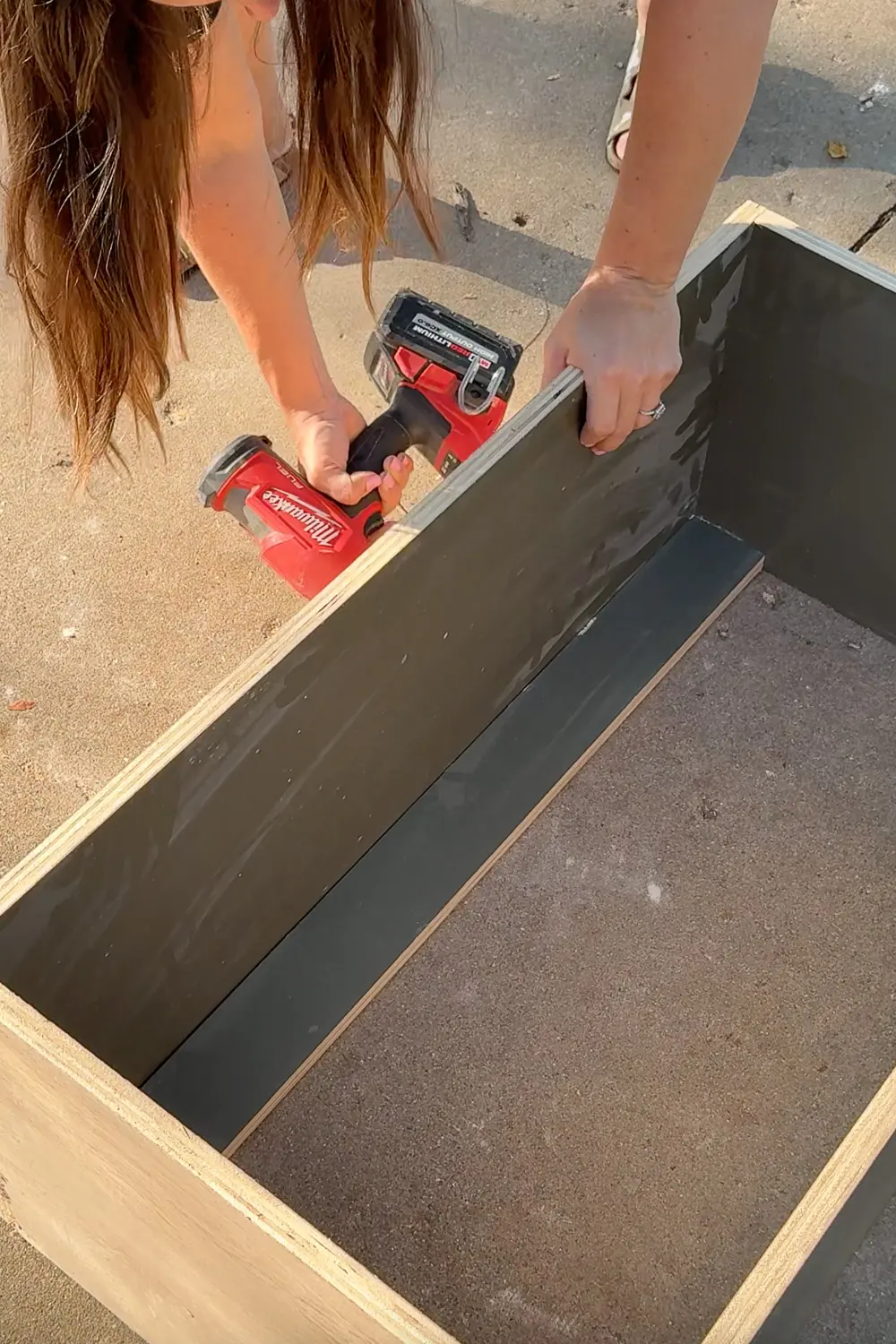 Securing the top stretcher to the bookshelf with a drill/driver while building custom DIY bookshelves for a home library.
