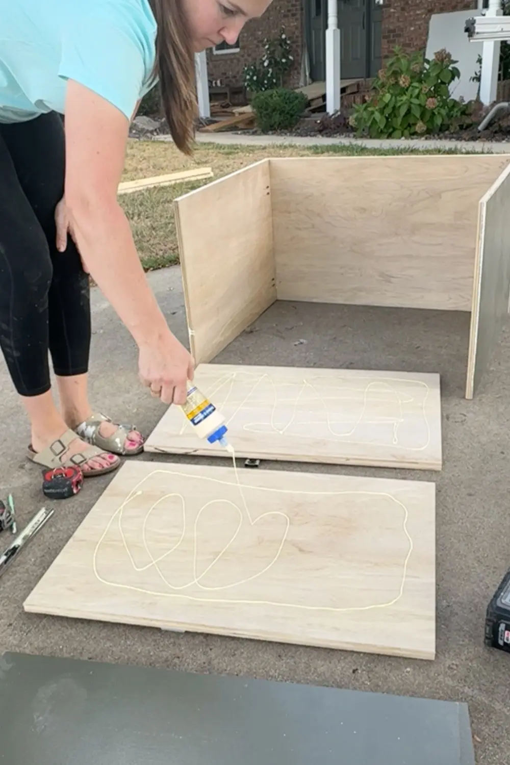 Applying wood glue to plywood panels before assembling a drawer box for the base cabinet in our DIY built-in bookshelves and cozy home library.