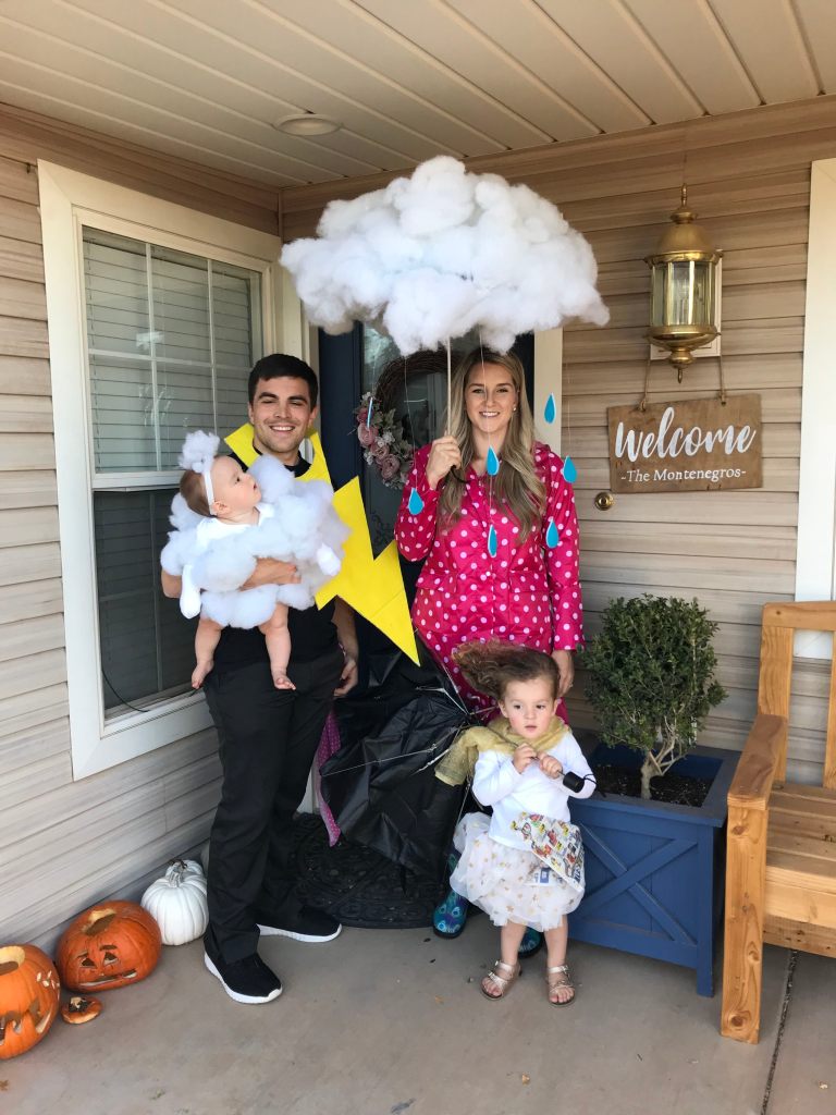 A woman dressed up as a cloud, a man dressed up as a lightning bolt, and two kids dressed up as cloudes