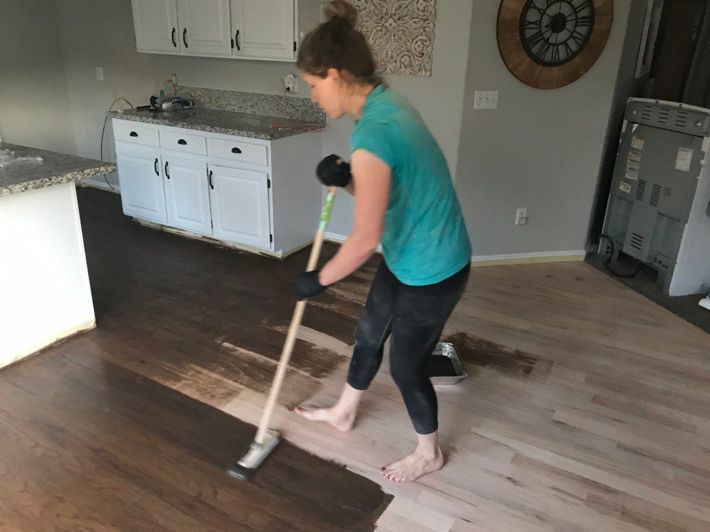 Woman staining a wood floor in a kitchen
