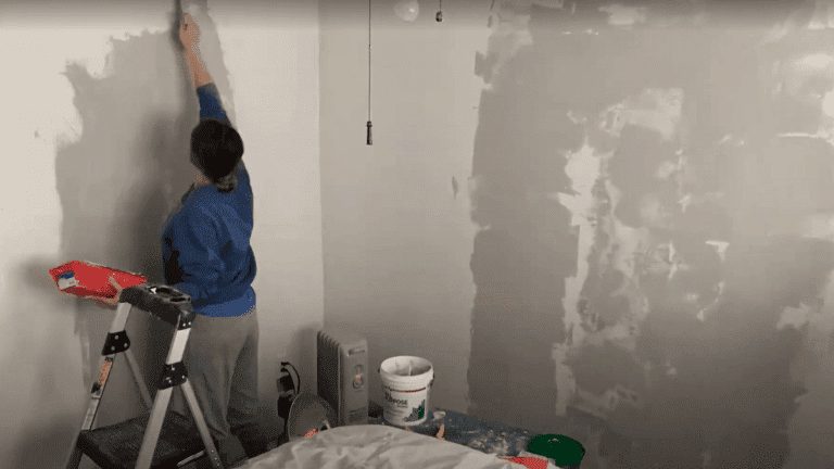 Woman fixing a bedroom wall with joint compound