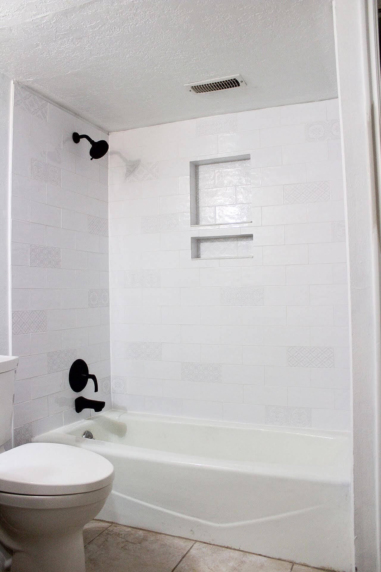 Finished bathroom remodel with white tile and black fixtures after removing mold from shower and rebuilding walls.