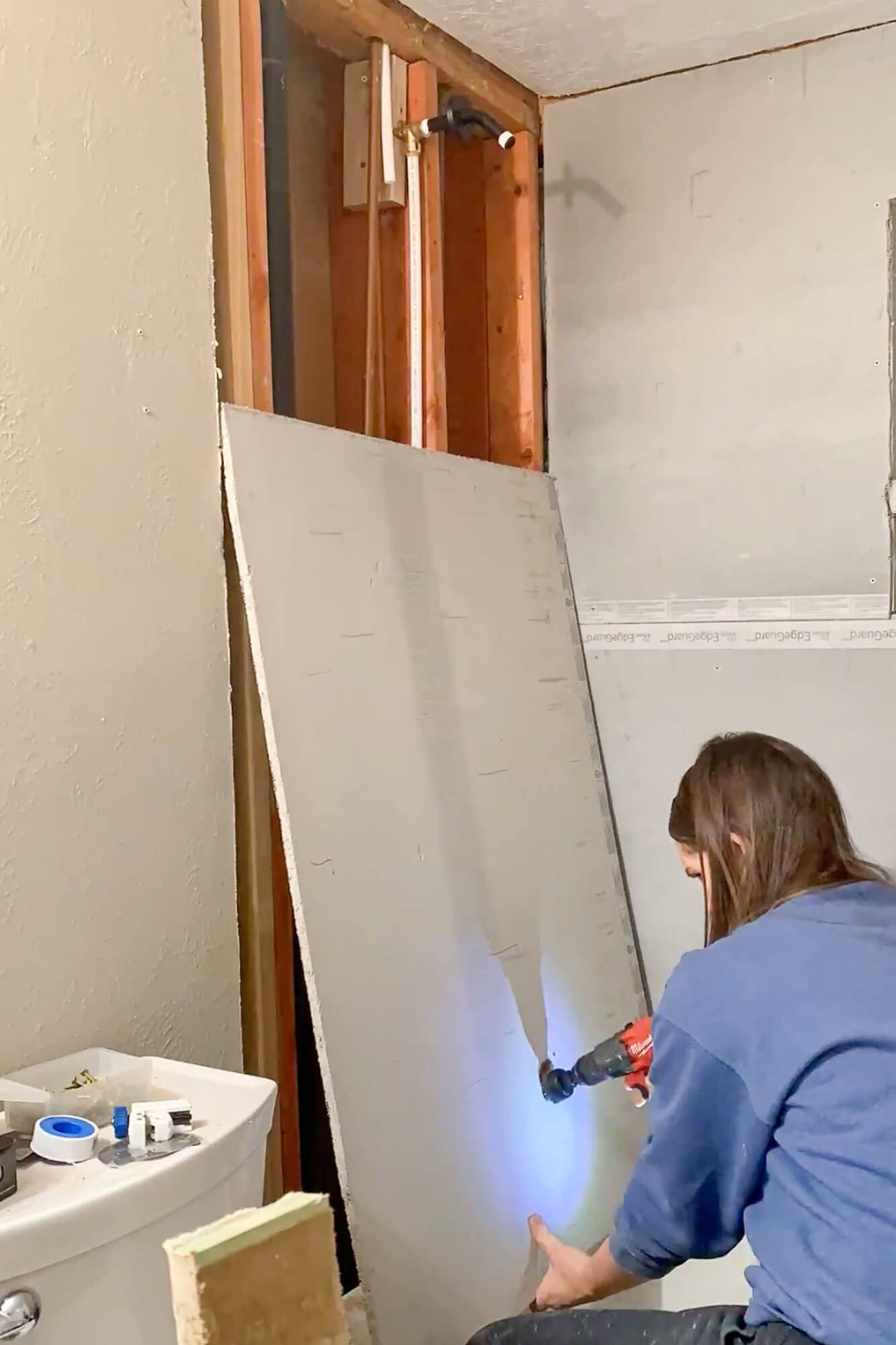Cutting a plumbing opening into cement board for shower rebuild.