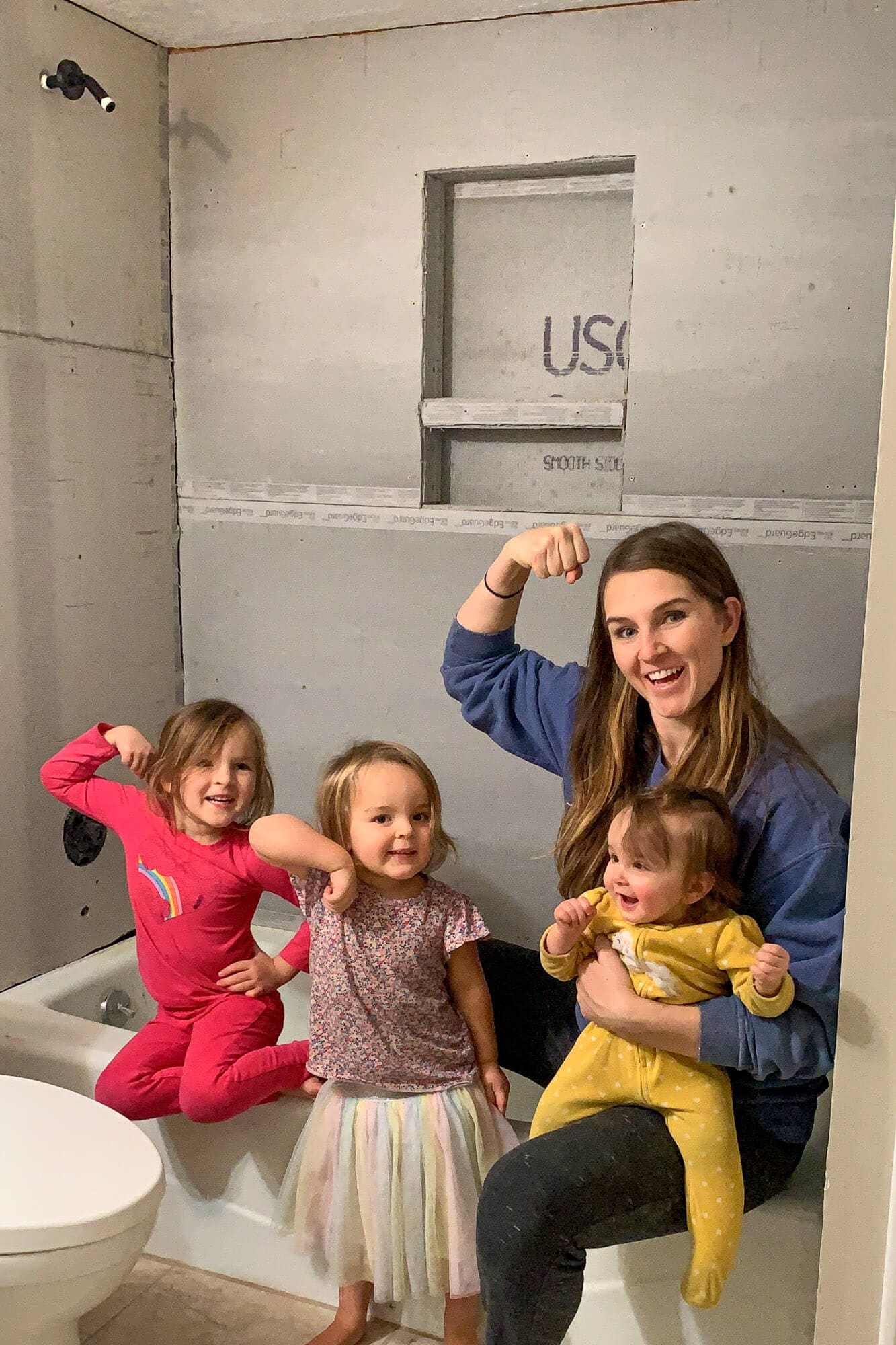 Family standing inside tub posing with cement board installed behind them