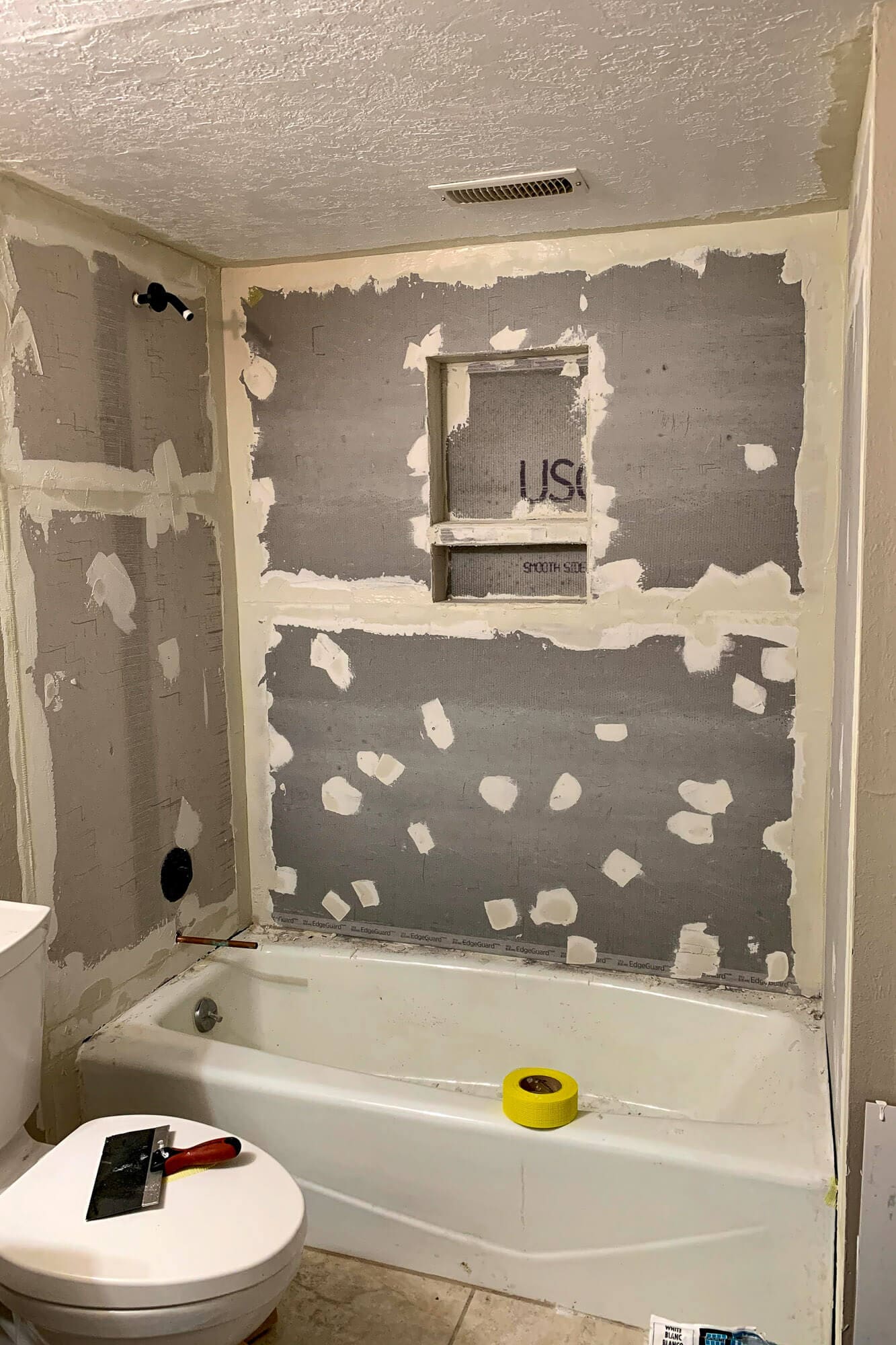 Shower mold removal prep—cement board installed with mesh tape and thinset over seams and screw heads, showing how to get rid of mold in a shower.