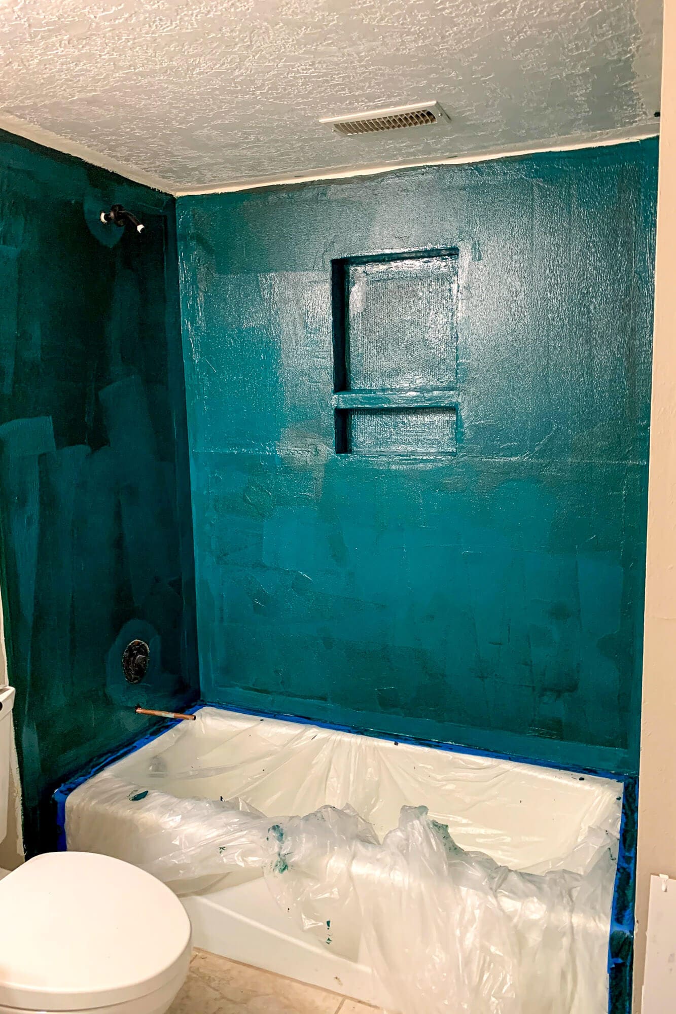 Shower walls fully coated in waterproofing membrane, ready for subway tile installation.