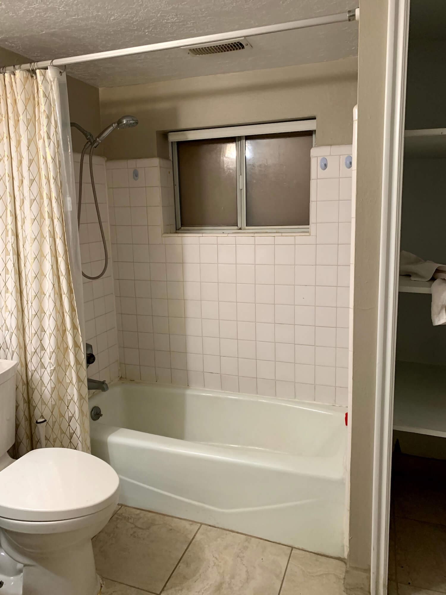 Before photo of shower with stained tile, cracked grout, and moisture damage.