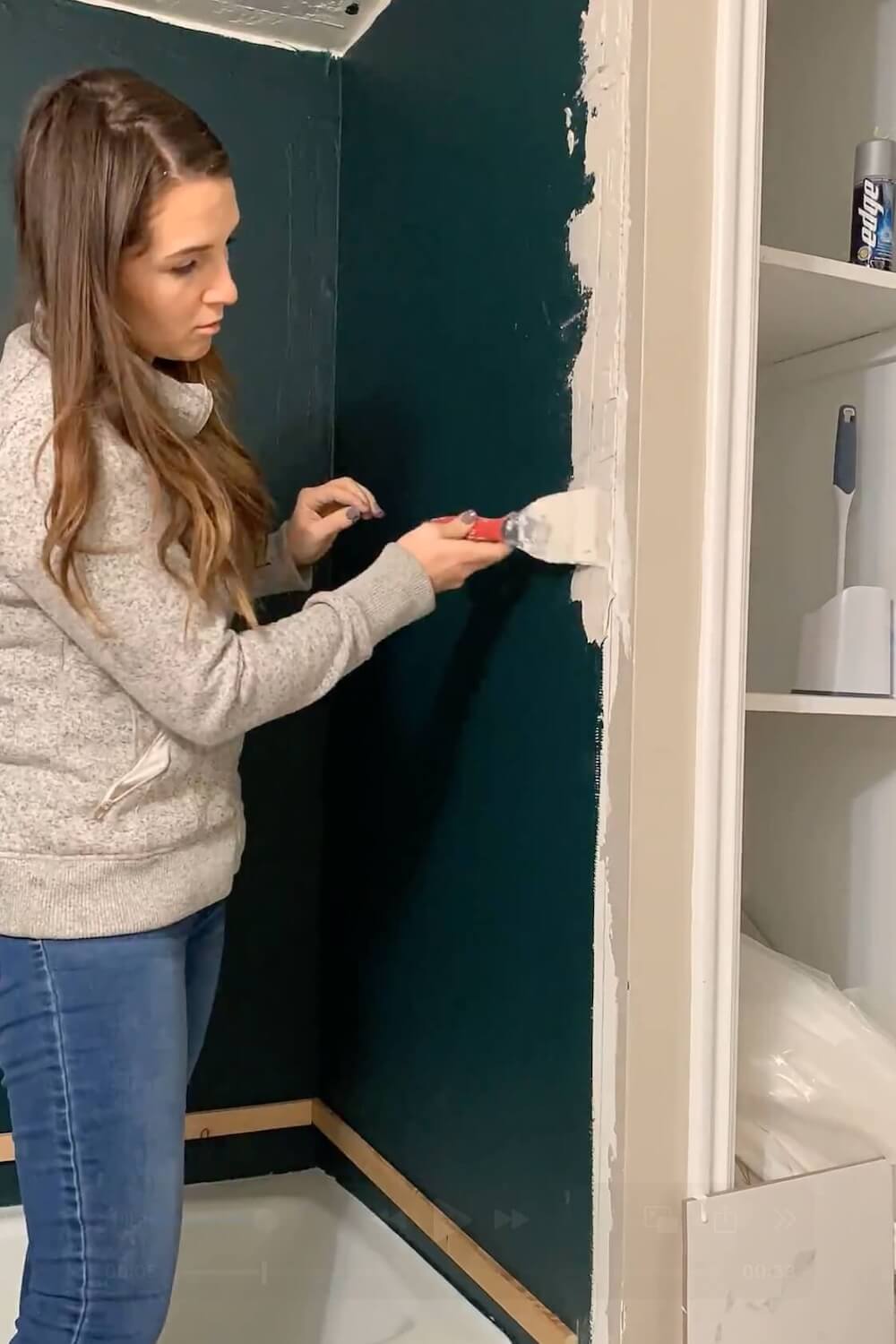 Applying thinset mortar along shower wall edge before tiling.