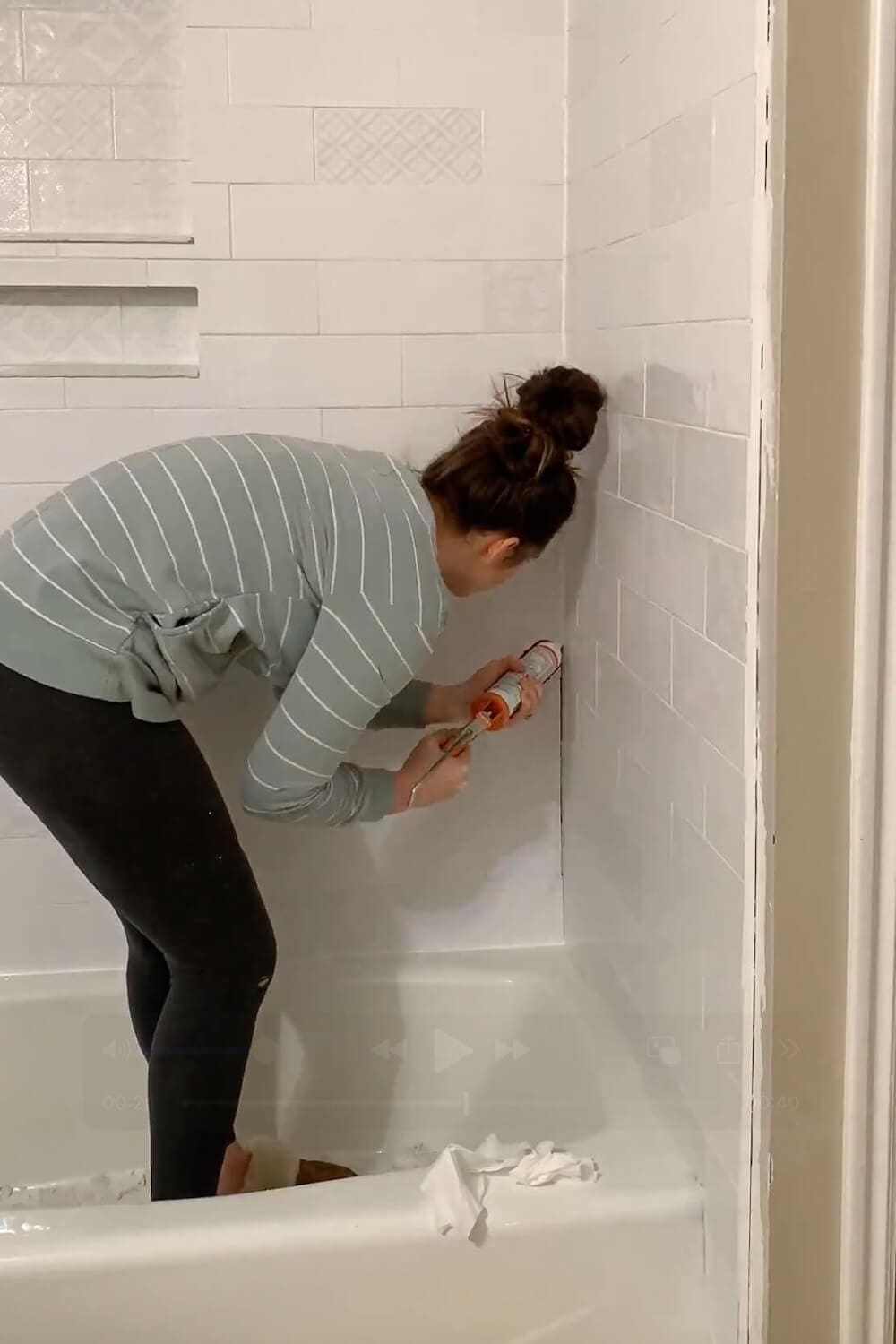 Caulking inside corner of tiled shower wall.