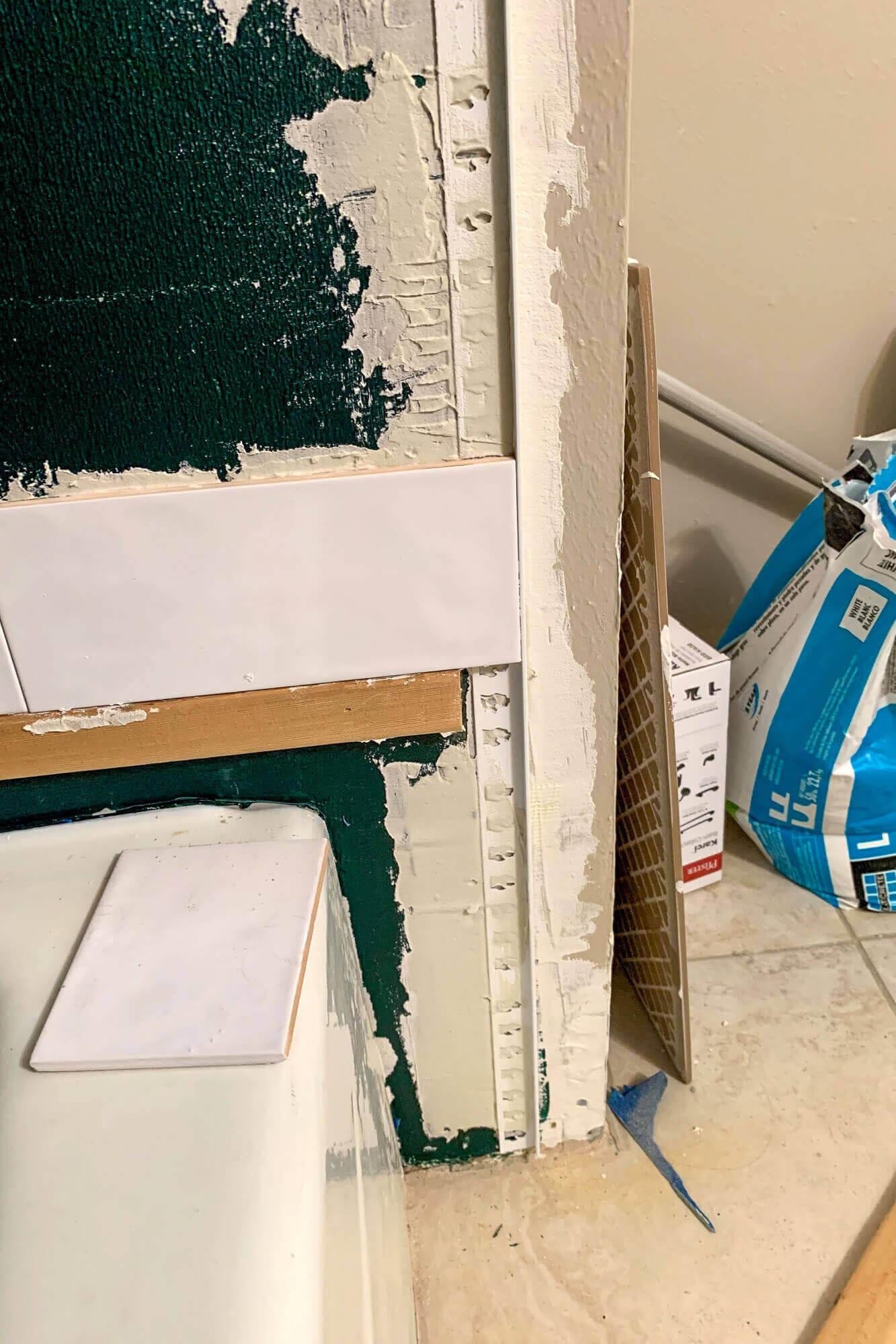 First row of white subway tiles resting on ledger board.