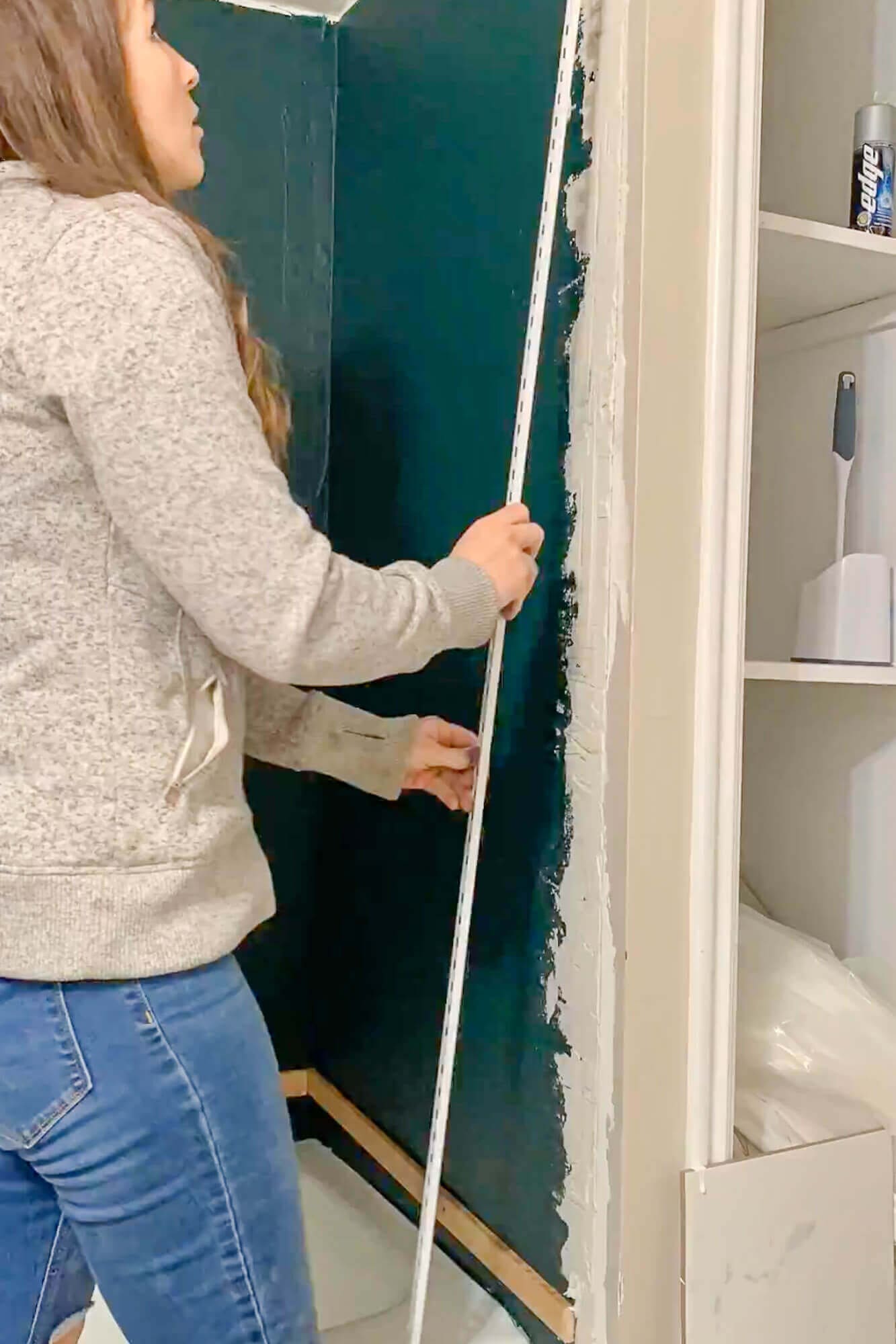 Installing metal tile edge trim on open shower corner.