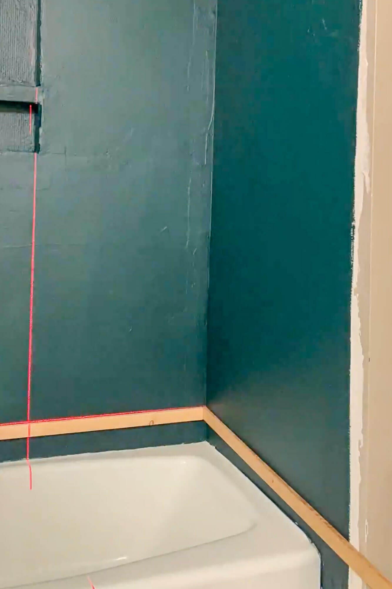 Close-up of ledger board aligned with laser level for tiling.