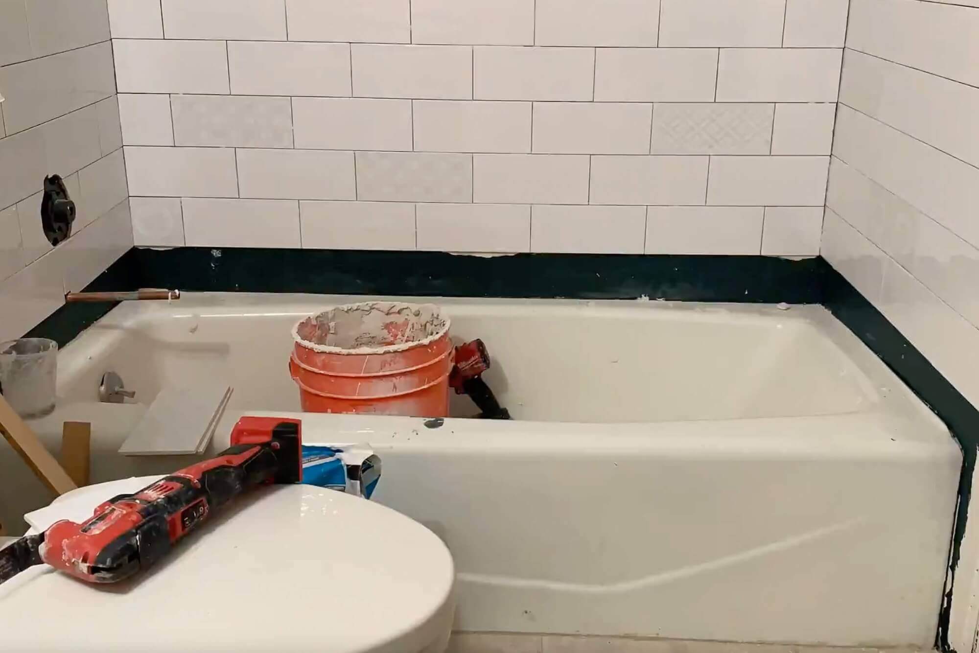 Measuring a cut tile to fit at the edge of the tub.