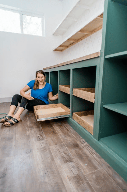 A woman sitting on the ground next to a drawer she just installed