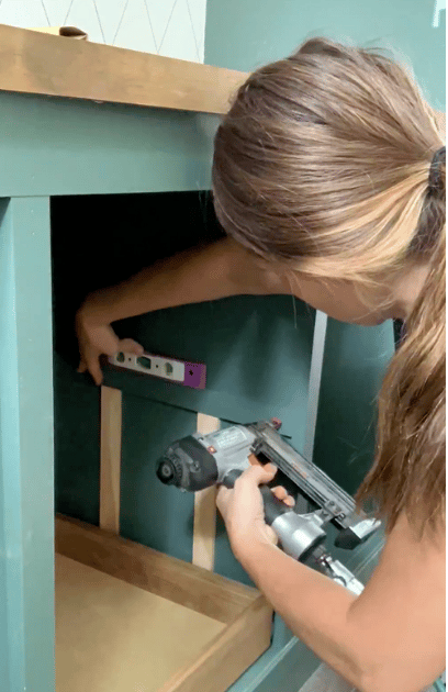 A woman installing spacers inside a cabinet