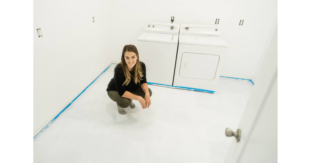Woman crouching in laundry room on white painted tile