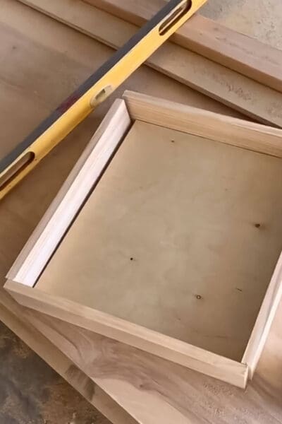 pine drawer pieces laid out on plywood with a level before assembling the drawer box