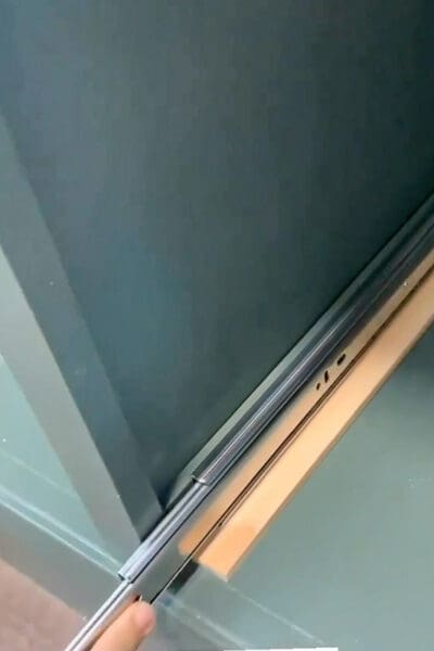 drawer slide mounted on a pine spacer inside a green cabinet