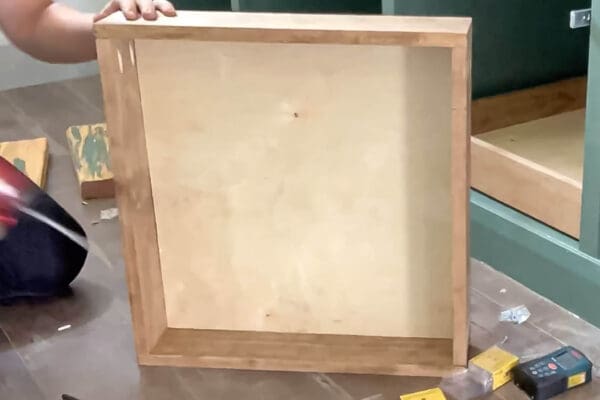 holding up a stained pine drawer box with a plywood base next to a green cabinet
