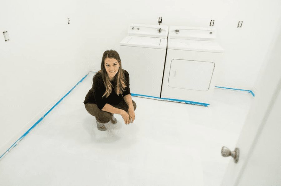 Woman crouching in laundry room on white painted tile