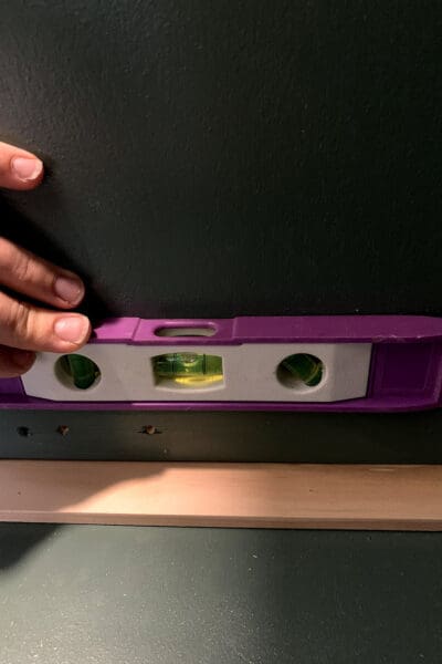 small level on a pine drawer spacer inside a green cabinet