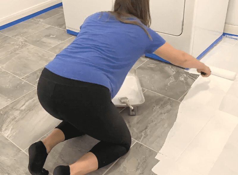 Woman painting laundry tile floor white