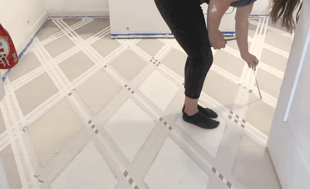 Woman peeling tape off a laundry room tile floor