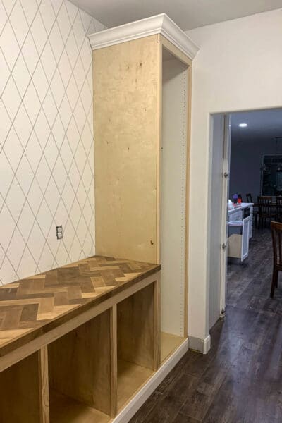 tall appliance cabinet with crown molding beside the herringbone counter before paint