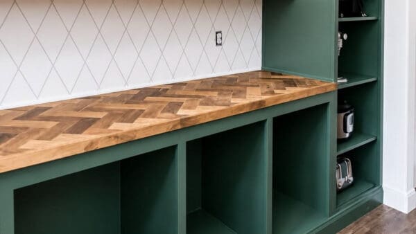   finished herringbone countertop on green open cubby cabinets next to a tall appliance cabinet