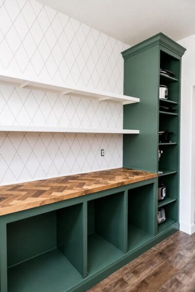 butler's pantry with a herringbone countertop, open cubbies, and a tall green appliance cabinet