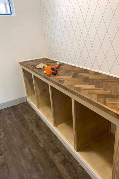 caulking the seams of the herringbone countertop and cubby cabinet before paint