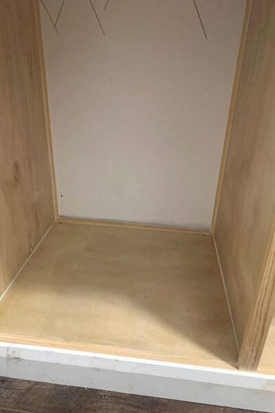 inside corner of a plywood cubby with trim along the bottom before caulk