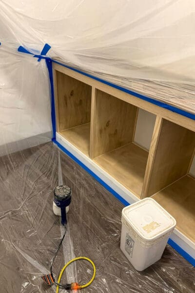 cubby cabinet taped off with plastic sheeting and painter's tape for spray paint