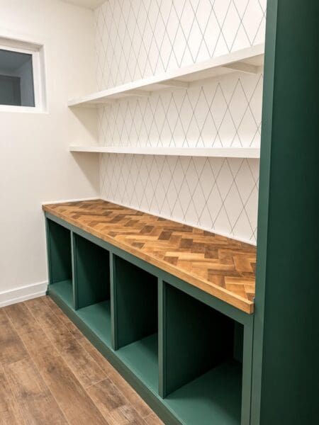 green butler's pantry with a herringbone countertop and white floating shelves