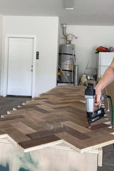 brad nailer attaching herringbone countertop boards to the cabinet top