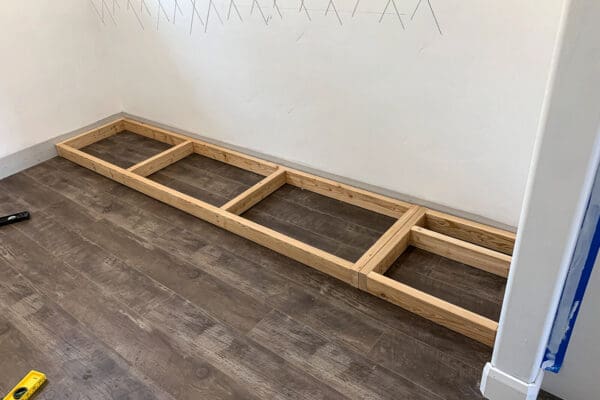 long 2x4 base screwed to the wall studs along the pantry floor