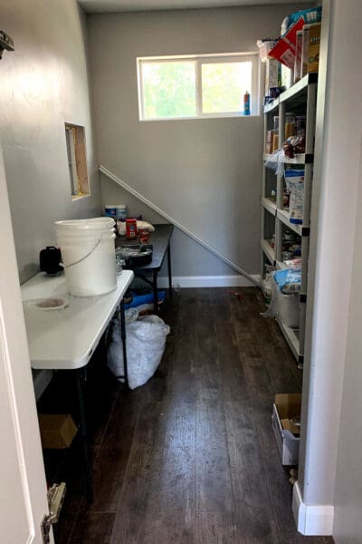 narrow pantry before the makeover with wire shelving and a folding table