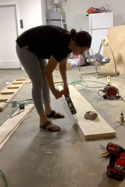 Crystel caulking the seams of a DIY floating shelf before sanding