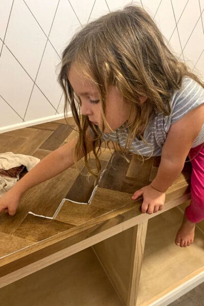 child pointing at clear caulk lines in the herringbone countertop seams