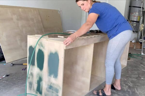 Crystel laying herringbone boards on top of a plywood cabinet in the garage